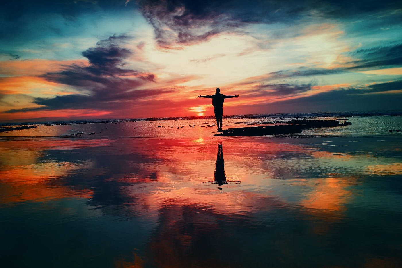 Man standing with arms out during sunset