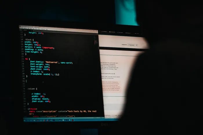 A blurred out person with their computer screen showing computer code.
