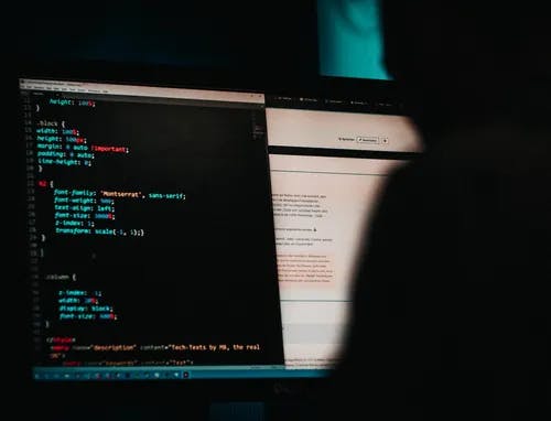 A blurred out person with their computer screen showing computer code.