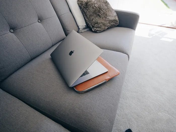 A macbook pro and a computer case on a couch. 