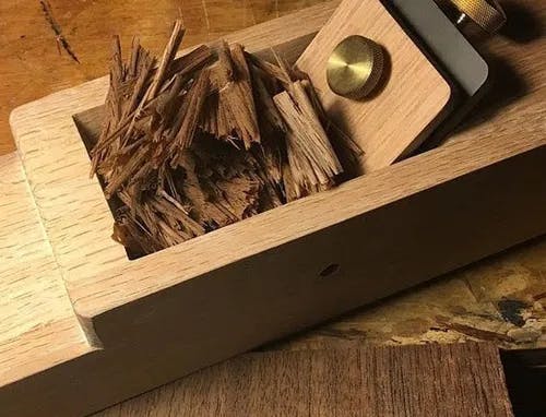 A block of wood with wood shavings inside of a compartment on a table.