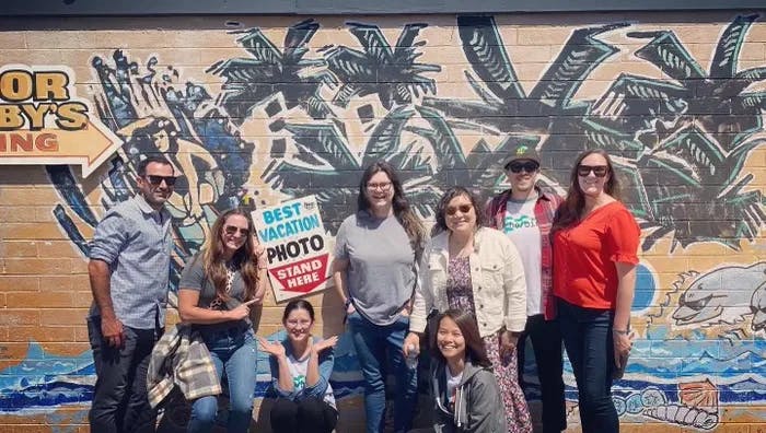a group of people standing in front of a mural