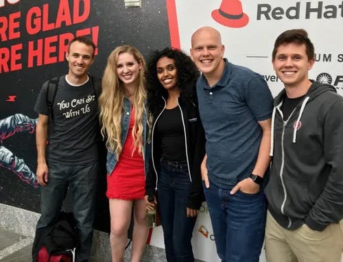 a group of people standing in front of a red hat sign