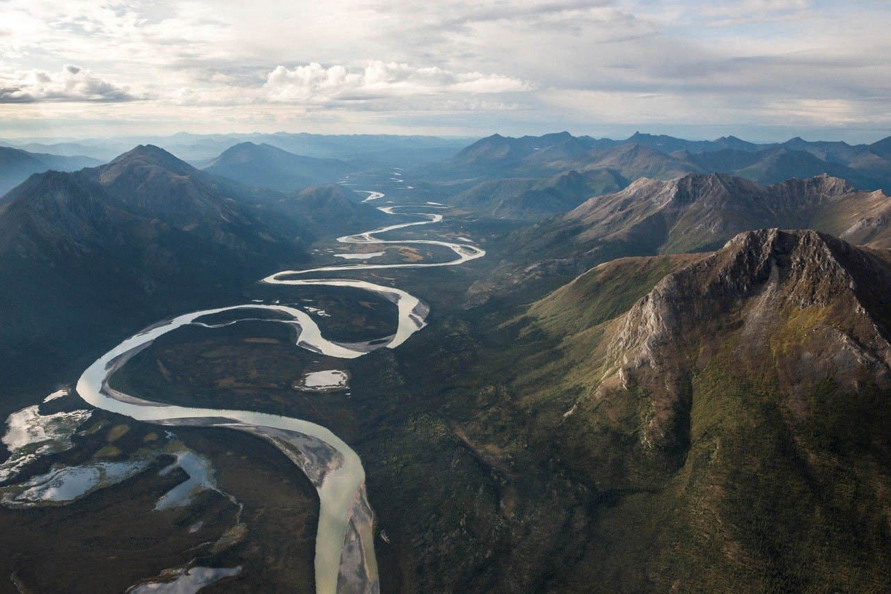 A small narrow pong river with large mountains being surrounded.