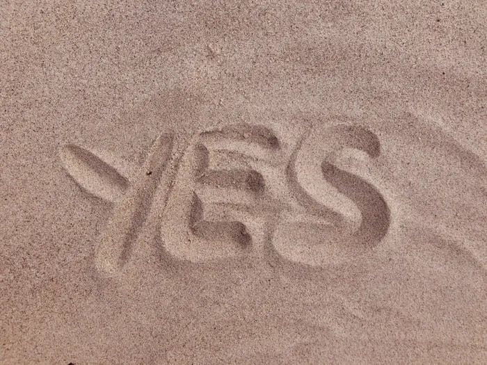 The word "yes" written in sand.