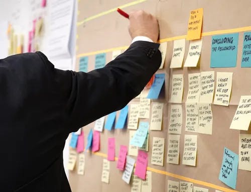 Man filling out board of post-its 