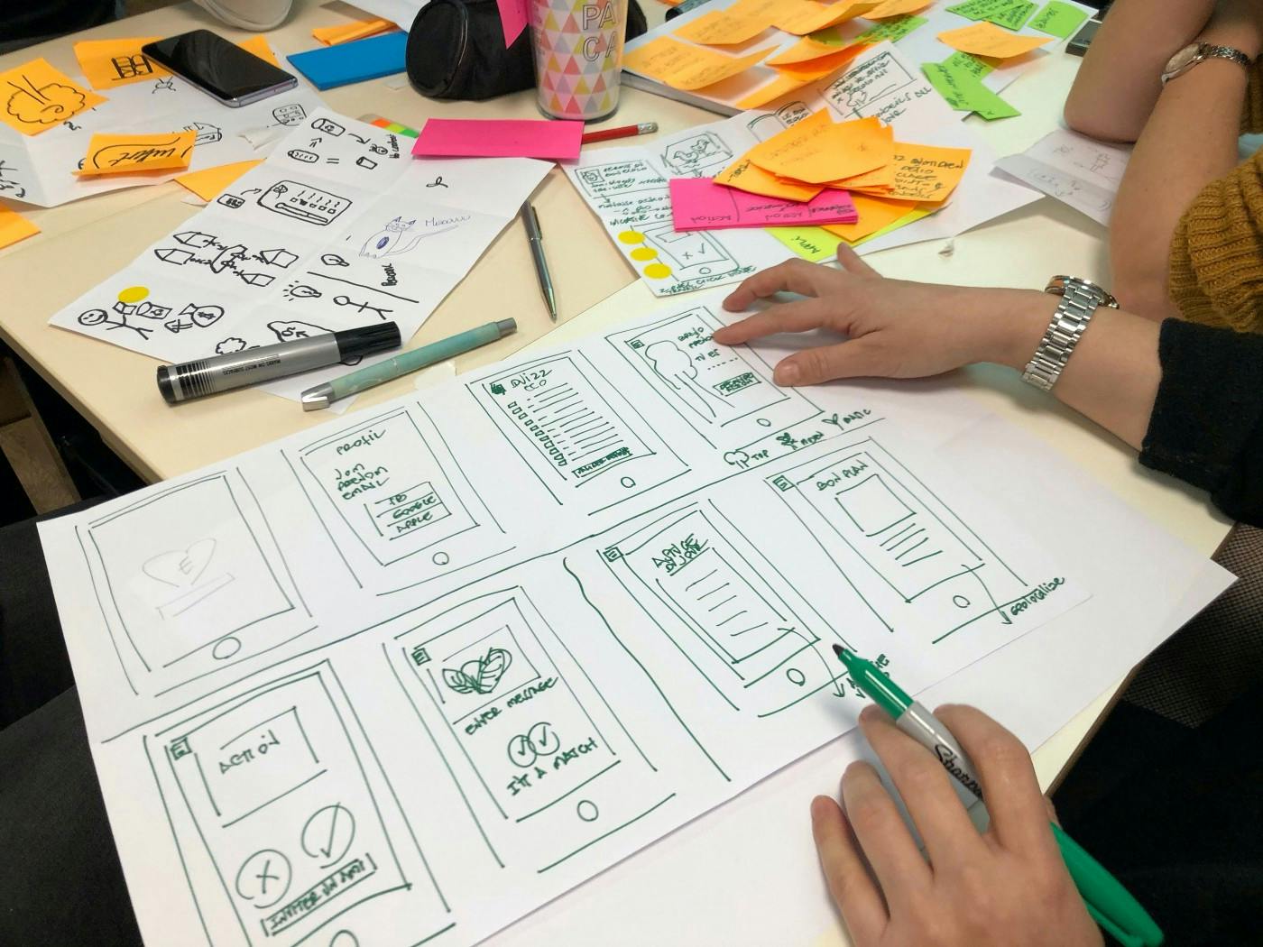 A table with diagrams, pens, and sticky notes for an app.