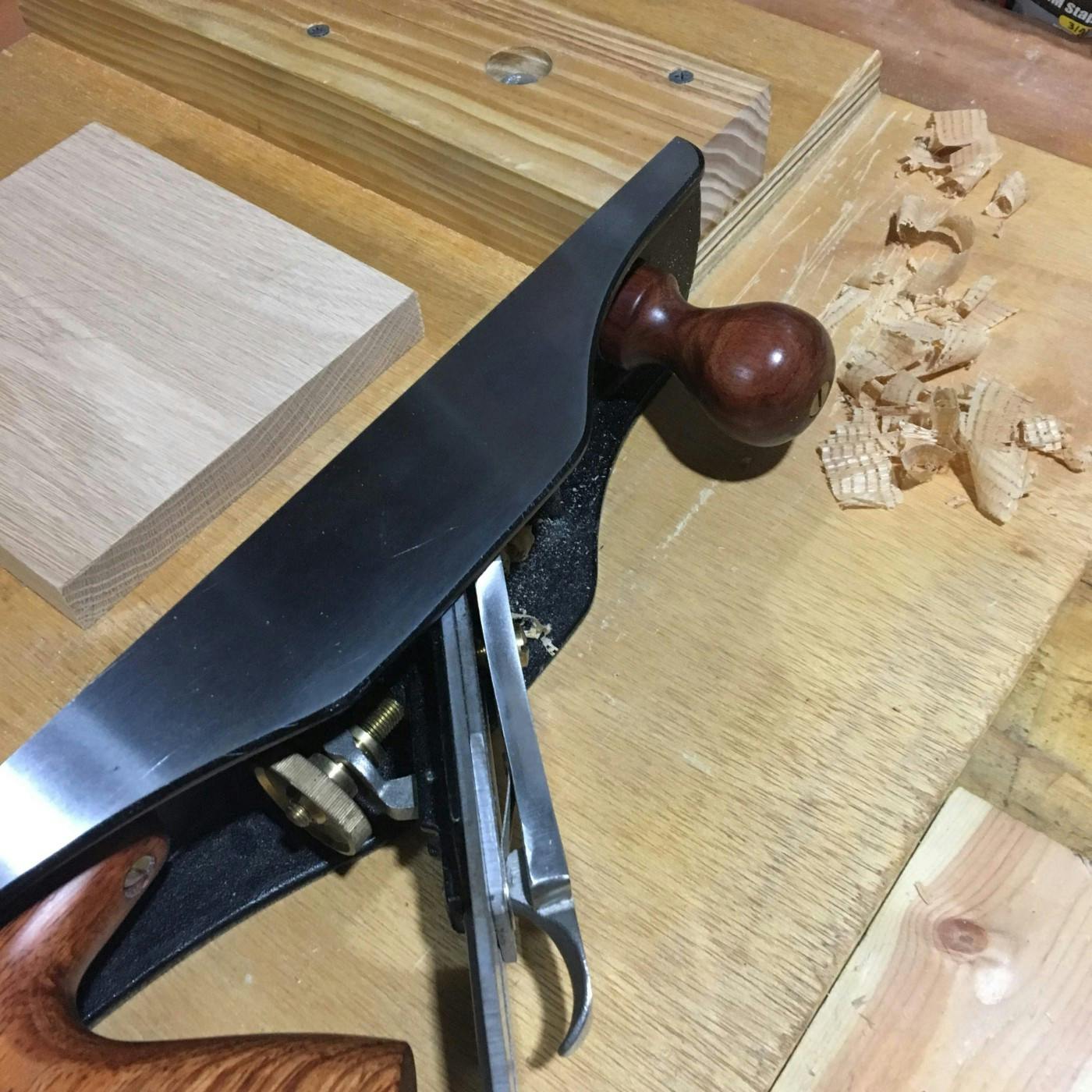 A wood table with a wood working tool and some wood shavings.