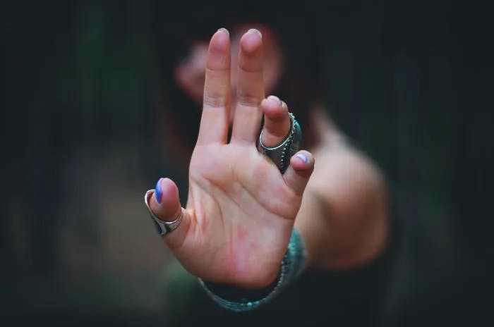 A person holding up their hand to the camera. 