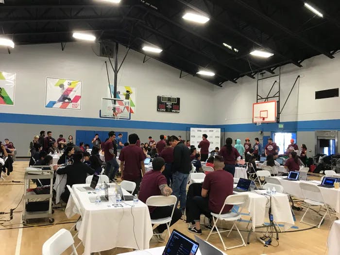 A gymnasium with people around tables and computers.