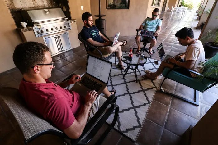 4 men sitting in a circle with laptops.