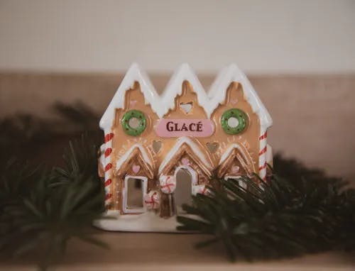 A gingerbread house with a pine garland around it.