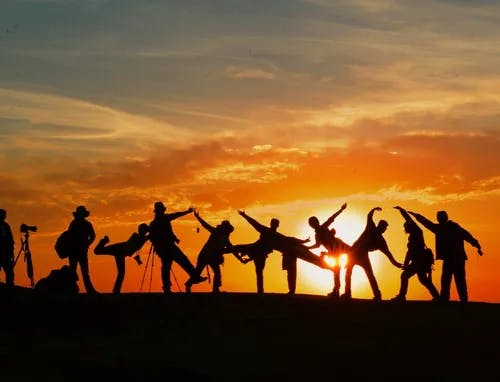 People dancing in-front of sunset
