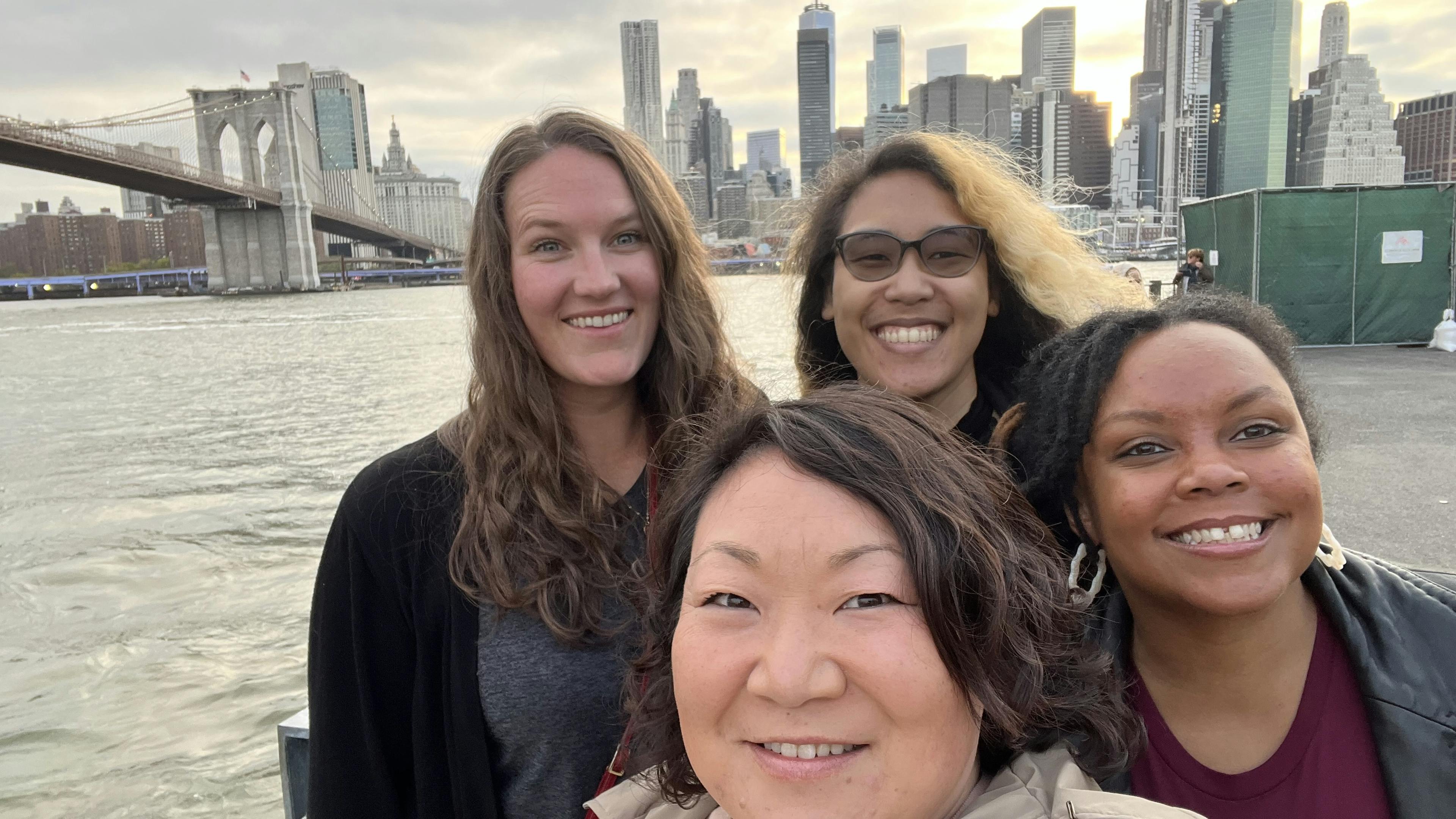 Women smile in front of water in New York
