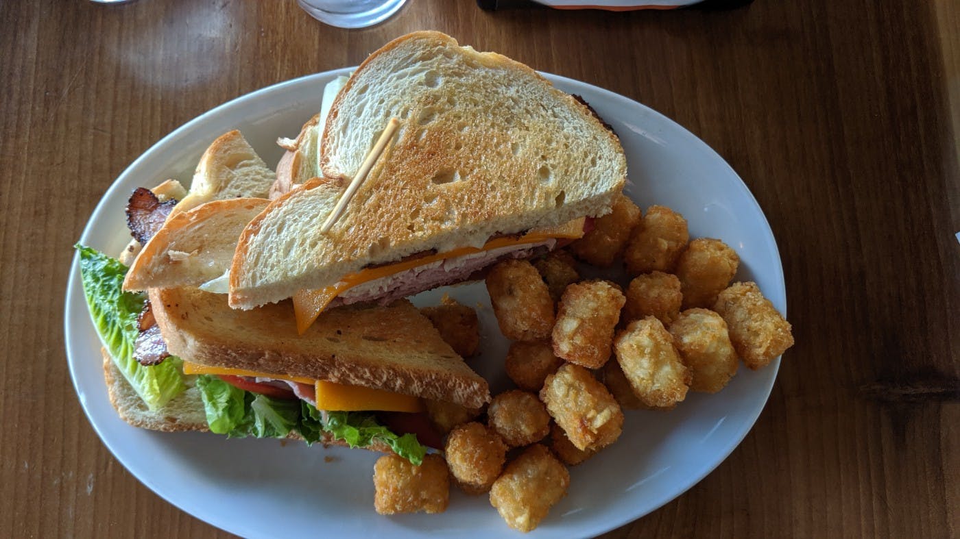Club sandwich and tater tots on a plate